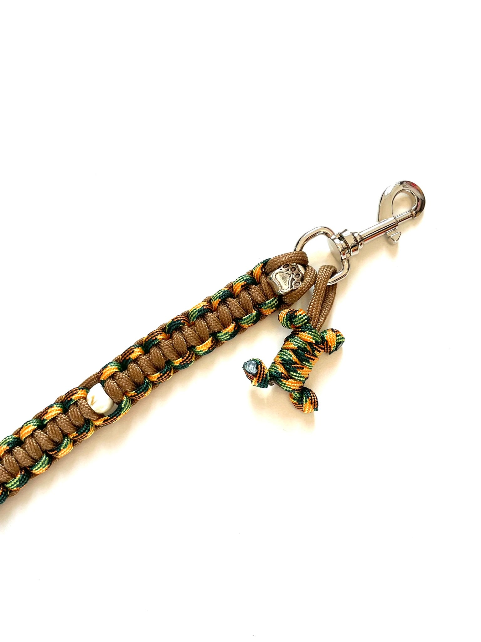 Laisse pour chien en paracorde solide et stylée. Couleurs : bronze, orange et vert, gros plan sur le mousqueton